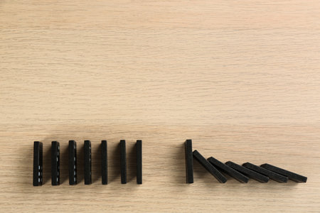 Black domino tiles on wooden background, flat lay. Space for textの写真素材