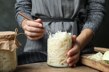 Woman with fermented cabbage at wooden table, closeupの写真素材