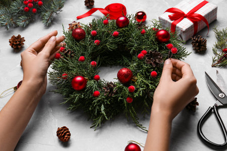 Florist making beautiful Christmas wreath at gray table, closeupの写真素材
