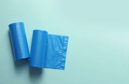 Rolls of turquoise garbage bags on light blue background, flat lay. Space for textの写真素材