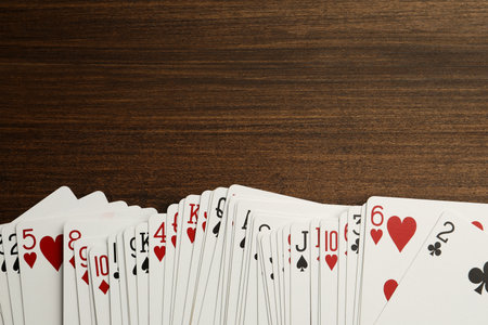 Deck of playing cards on wooden table, top view. Space for text