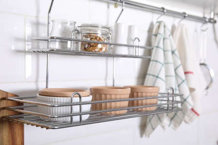 Many different ramekins on metal rack in kitchen