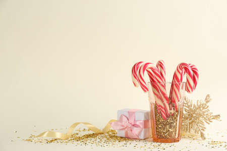 Christmas candy canes, gift box and confetti on beige background, space for textの写真素材