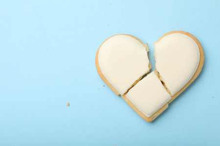 Broken heart shaped cookie on light blue background, top view with space for text. Relationship problems conceptの写真素材