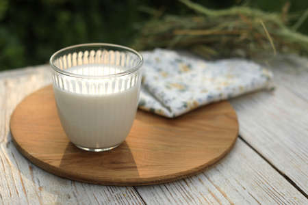 Glass of tasty fresh milk on white wooden table outdoors, space for textの写真素材