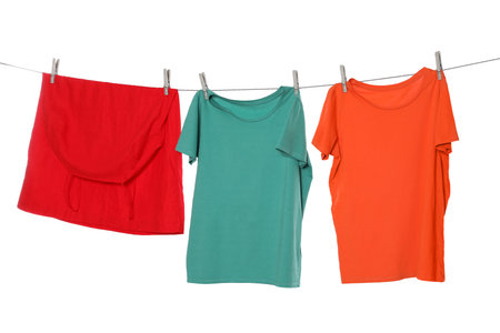 Different bright clothes drying on washing line against white backgroundの写真素材