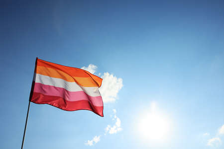 Bright lesbian flag fluttering against blue sky. Space for textの写真素材