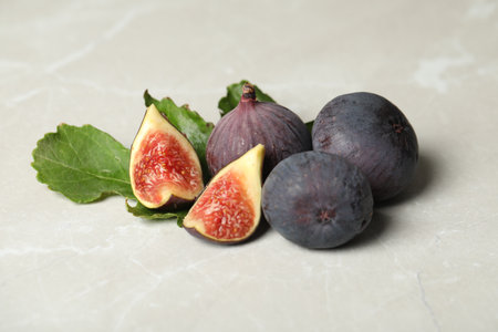 Tasty raw figs and green leaf on light gray marble table, closeupの写真素材