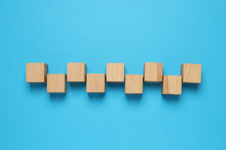 Wooden cubes on light blue background, flat layの写真素材