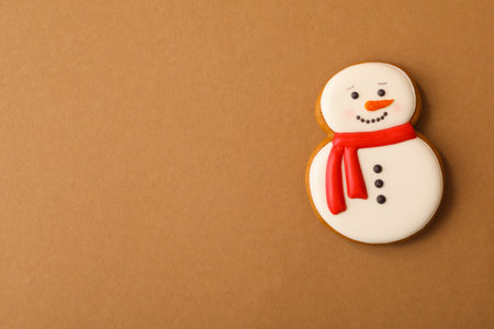 Christmas snowman shaped gingerbread cookie on brown background, top view. Space for textの写真素材