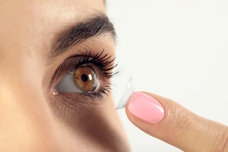 Young woman putting contact lens in her eye, closeupの写真素材