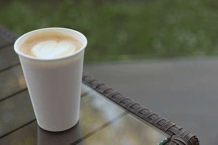 Cardboard takeaway cup of coffee on glass table outdoors, space for textの写真素材