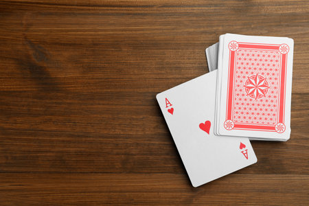 Deck of playing cards on wooden table, flat lay. Space for text