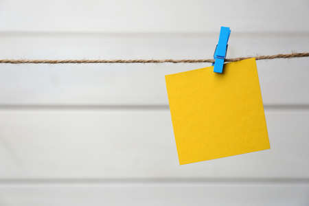 Clothespin with blank notepaper on twine against white wooden background. Space for textの写真素材