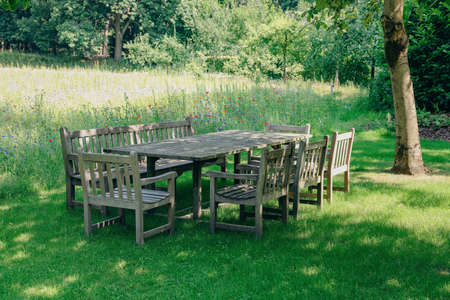 Empty wooden table with bench and chairs on sunny day outdoorsの写真素材
