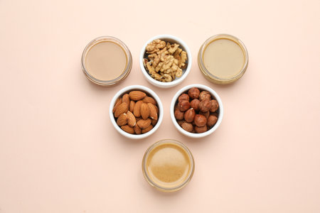 Different types of delicious nut butters and ingredients on beige background, flat layの写真素材