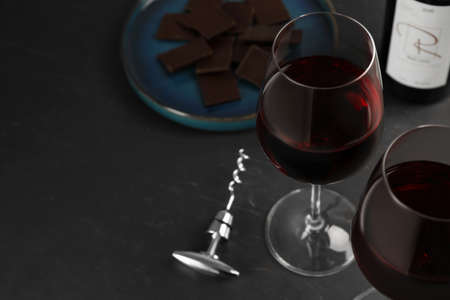 Tasty red wine and chocolate on black table. Space for textの写真素材