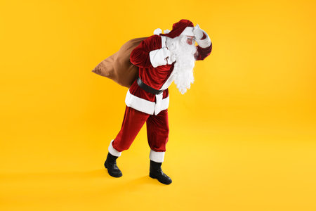Full length portrait of Santa Claus with sack on yellow backgroundの写真素材