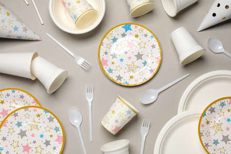Disposable tableware on light gray background, flat lay