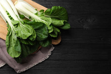 Fresh green pak choy cabbages on black wooden table, top view. Space for textの写真素材