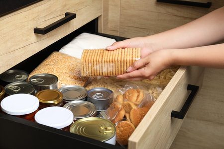 Woman taking food out from open drawer indoors, closeupの写真素材