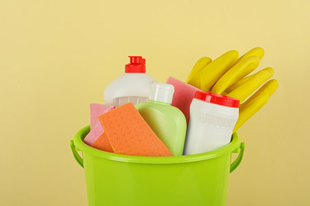Bucket with different cleaning supplies against beige background, closeupの写真素材