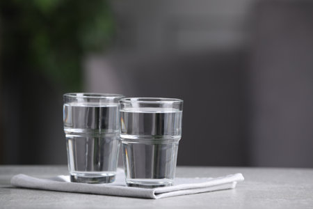 Glasses of clean water on light gray table indoors, space for textの写真素材
