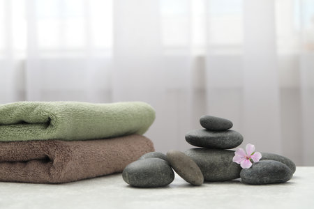 Spa stones, fresia flower and towels on white table indoorsの写真素材