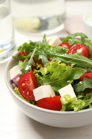 Delicious salad with arugula and vegetables on white table, closeupの写真素材