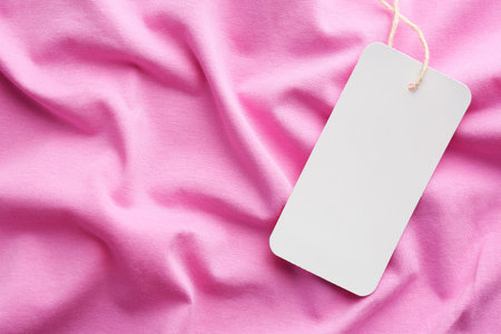 Cardboard tag with space for text on pink fabric, top viewの写真素材