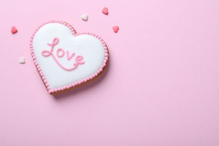 Heart shaped cookie with word Love on pink background, flat lay and space for text. Valentine's day treatの写真素材