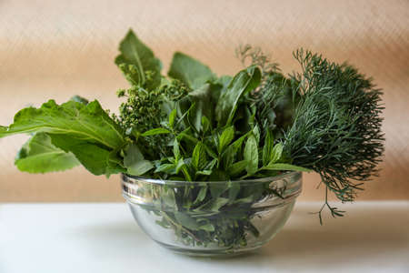 Different herbs in bowl on white wooden tableの写真素材