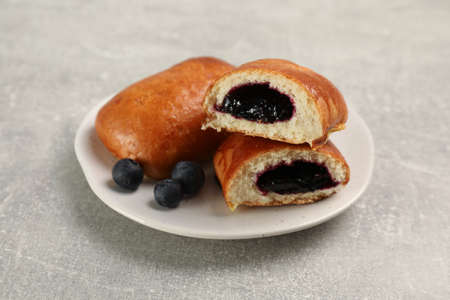Delicious baked patties with blueberries on light gray table