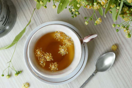 Cup of aromatic tea with linden blossoms on white wooden table, flat layの写真素材