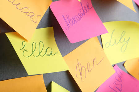 Paper notes with different baby names on gray wallの写真素材