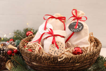 Bags with gifts in basket and festive decor on table, closeup. christmas advent calendar