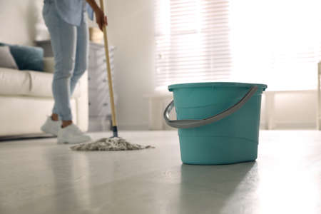 Plastic bucket and woman mopping floor in living room, closeup. cleaning suppliesの写真素材