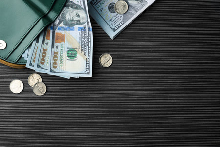 Dollar banknotes, coins and wallet on black wooden table, flat lay with space for text. money exchangeの写真素材