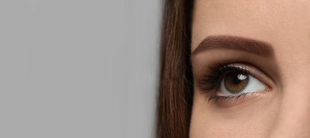 Closeup view of woman with beautiful eyes on light gray background, space for text. banner design