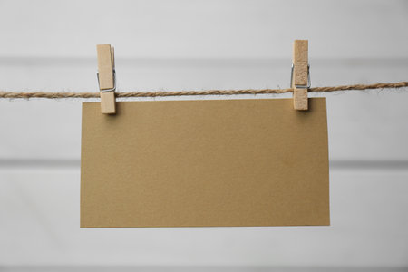 Clothespins with blank notepaper on twine against white wooden background. Space for textの写真素材