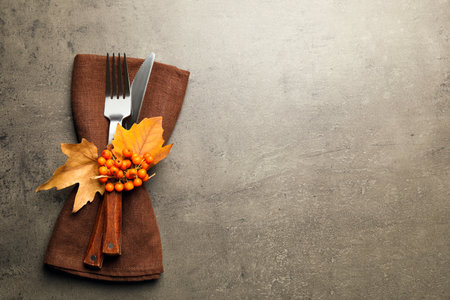 Top view of cutlery with napkin, ashberries and autumn leaves on gray table, space for text. Thanksgiving Dayの写真素材