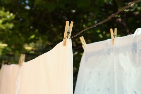 Washing line with clean laundry and clothespins outdoors, closeupの写真素材
