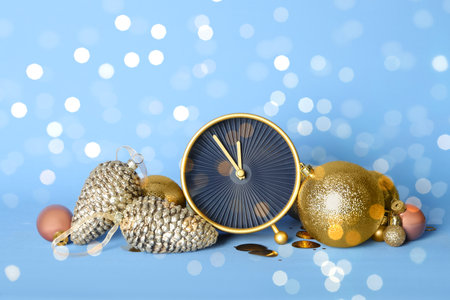 Stylish clock with Christmas decor on light blue background. New Year count down
