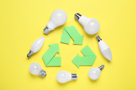 Recycling symbol and light bulbs on yellow background, flat layの写真素材