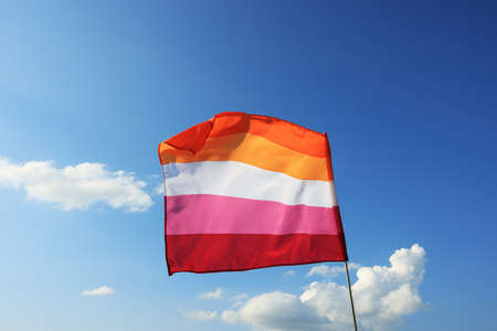 Bright lesbian flag fluttering against blue skyの写真素材