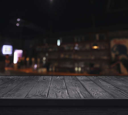 Empty black wooden surface and blurred view of bar interior. space for designの写真素材