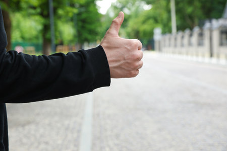 Man catching car on city street, closeup. Hitchhiking tripの写真素材