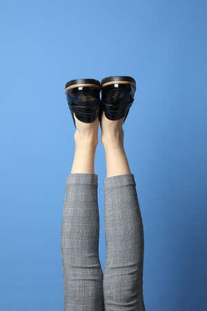 Woman wearing stylish shoes on blue background, closeup