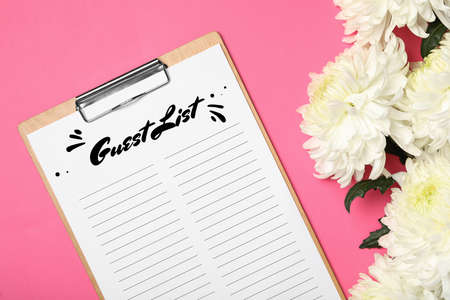 Guest list and beautiful white chrysanthemum flowers on pink background, flat layの写真素材