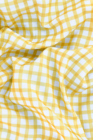 Yellow checkered picnic tablecloth as background, top viewの写真素材